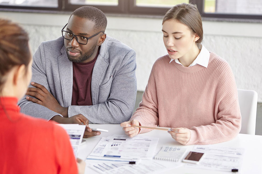 A bank advisor reviewing loan documents with customers at a desk