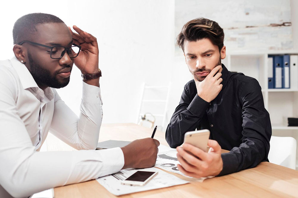 A bank customer reviewing unrecognized transactions on his phone with a support specialist