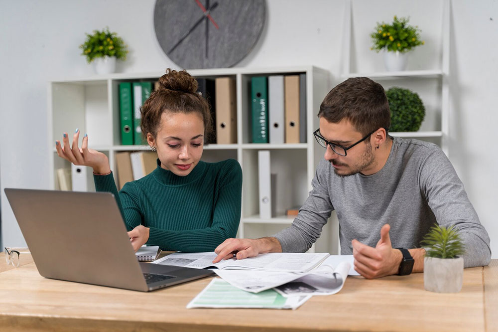 A student and an advisor reviewing financial-aid paperwork together at a desk with a laptop