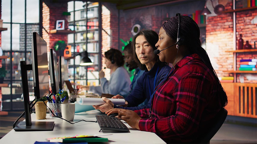 Student-services advisors on headsets working across multiple screens in a busy university service center